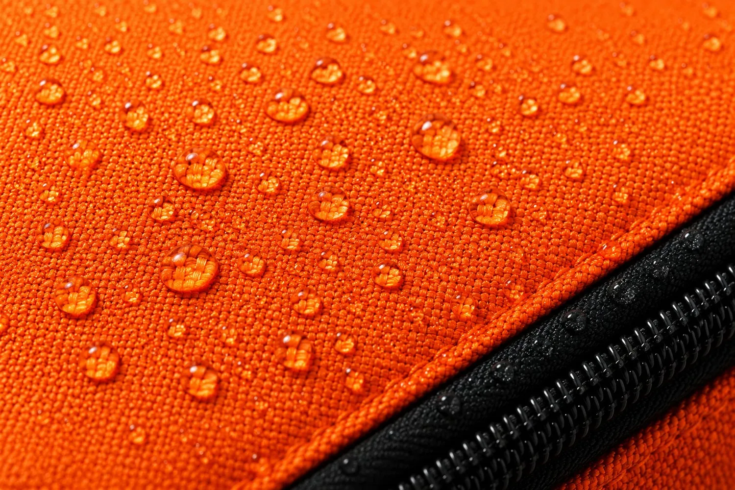 Water beading on the water-repellent shell fabric beside a sealed zipper