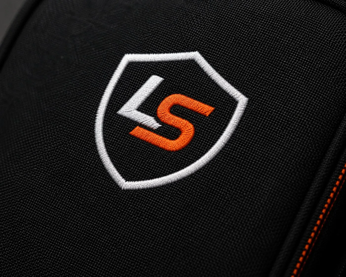 Embroidered LaunchShell shield badge on black ballistic weave